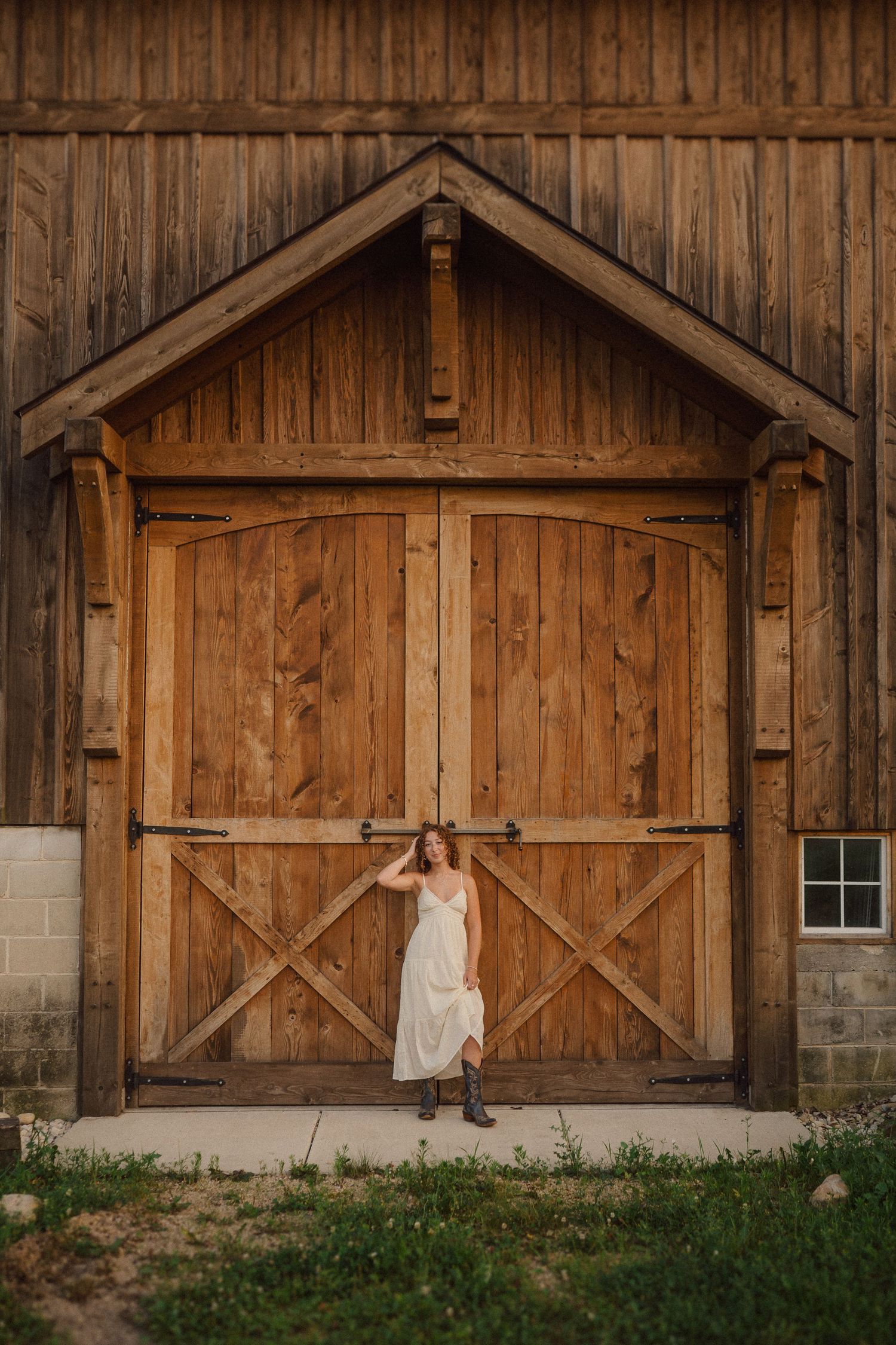 Rustic wooden barn with cross-braced doors and stone foundation in warm lighting.