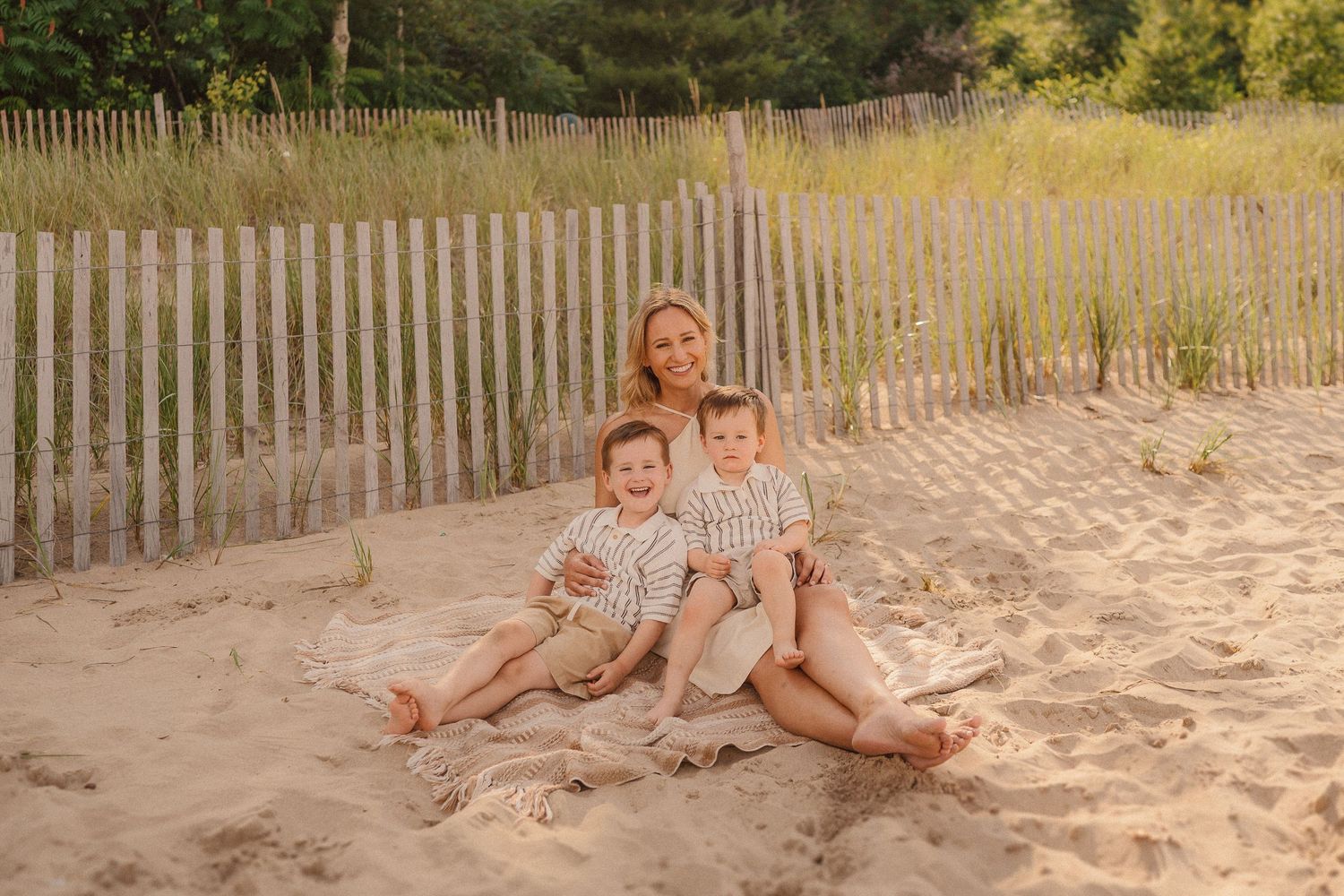 A relaxing summer scene on a sandy beach with weathered wooden fencing and green foliage in the background.