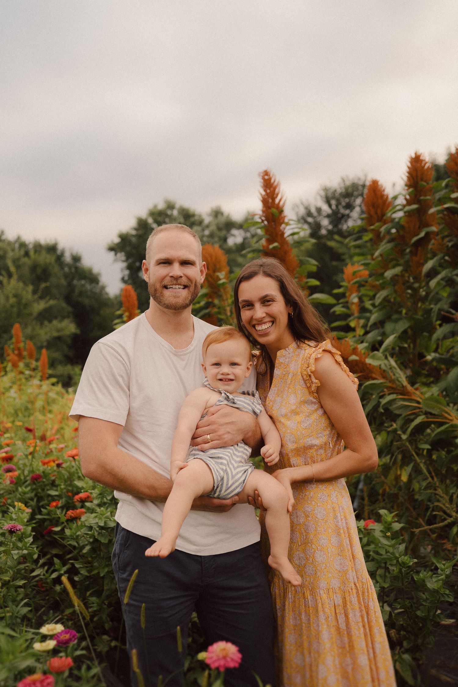 A family gathering in front of flowering amaranth plants during golden hour at a garden.