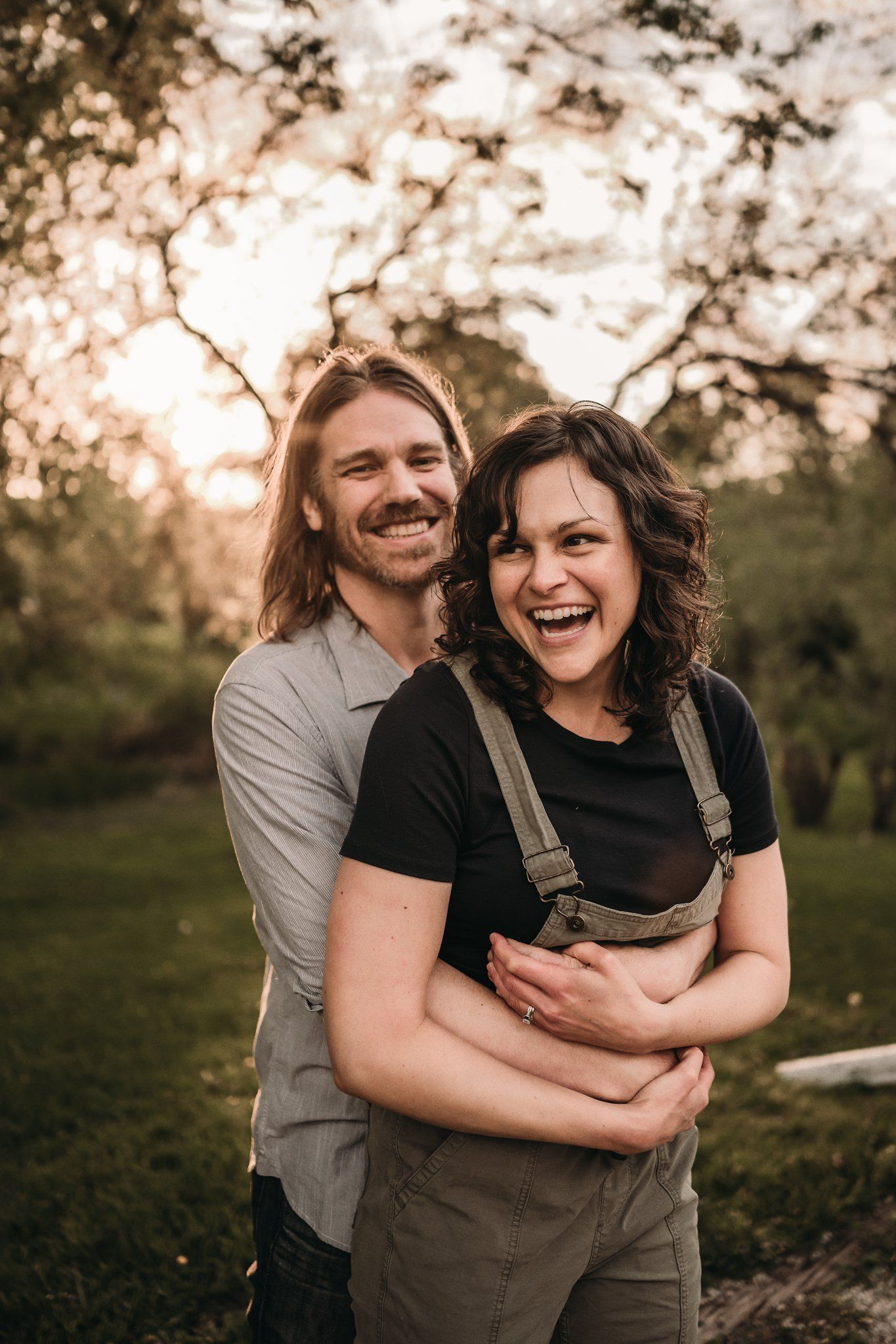 Happy couple sharing a joyful embrace in an outdoor setting during sunset.