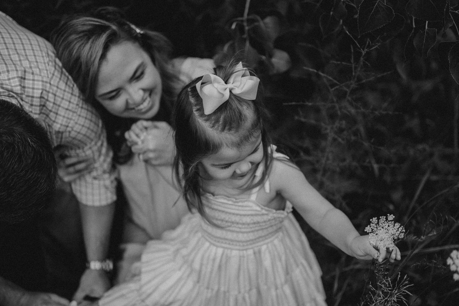 Black and white candid moment of joy captured between child and parent outdoors.