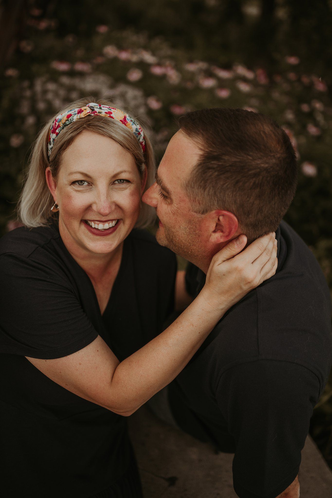 A romantic moment shared between a couple wearing black, with the woman in a floral headband.