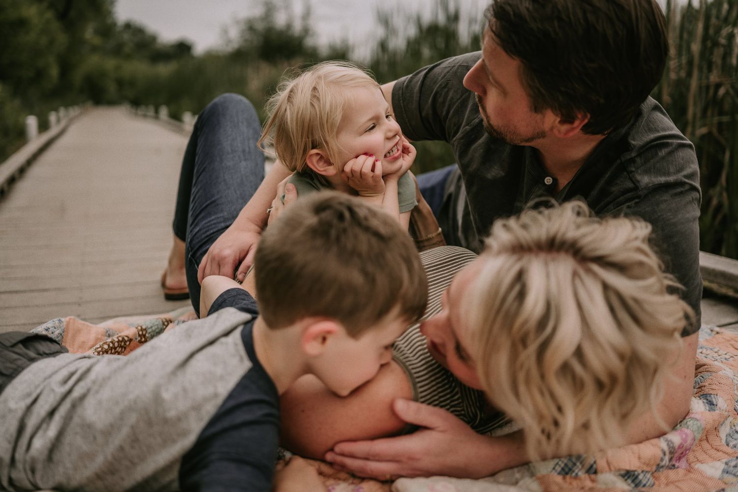 Family members lying down together and sharing a playful moment outdoors.
