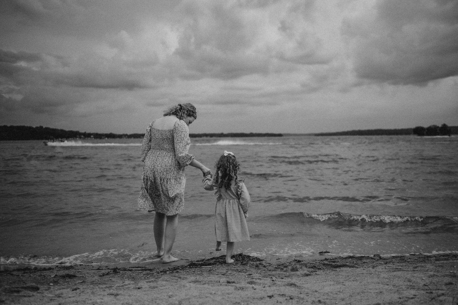 A poignant black and white moment of two figures looking out at the beach waves.