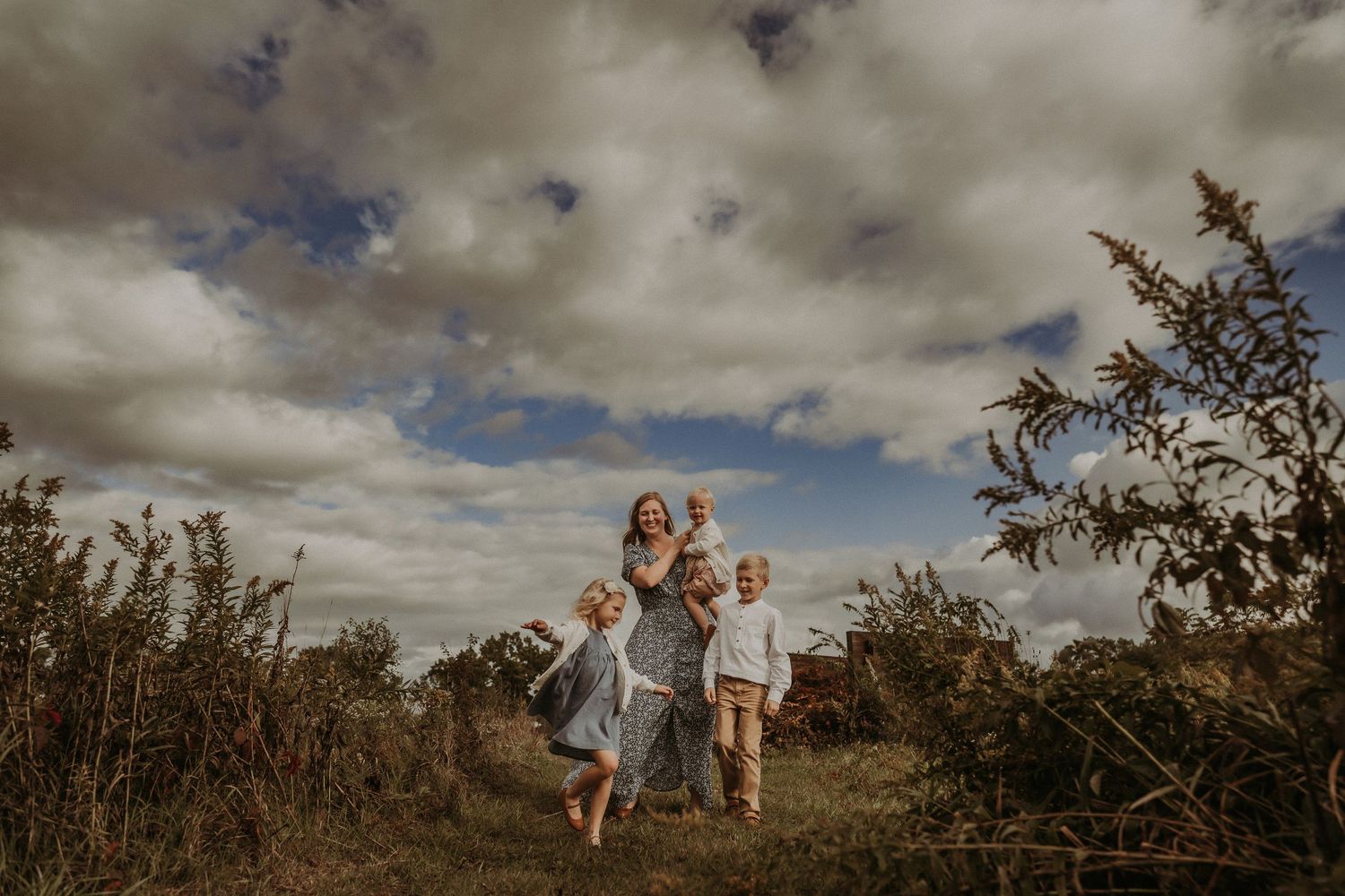 A joyful family moment captured while running through a field under moody skies.