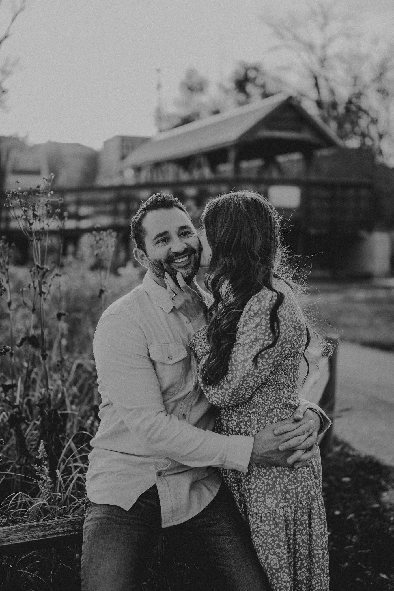 A romantic black and white moment captured between a couple embracing in a garden setting.