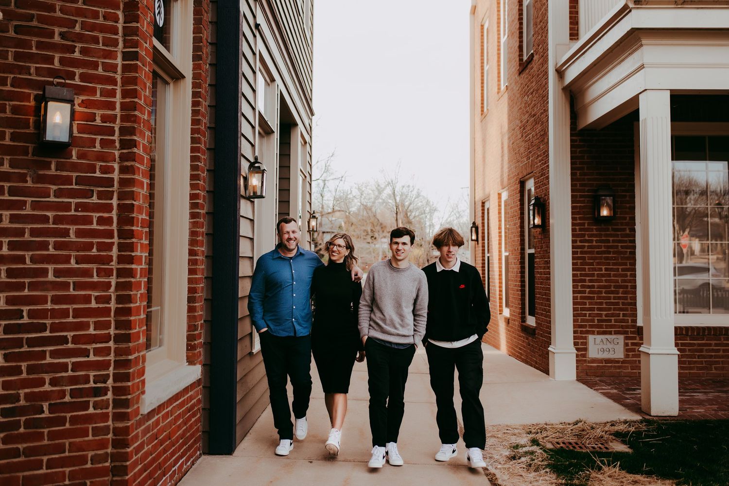 Group walking together on sidewalk between traditional brick buildings.