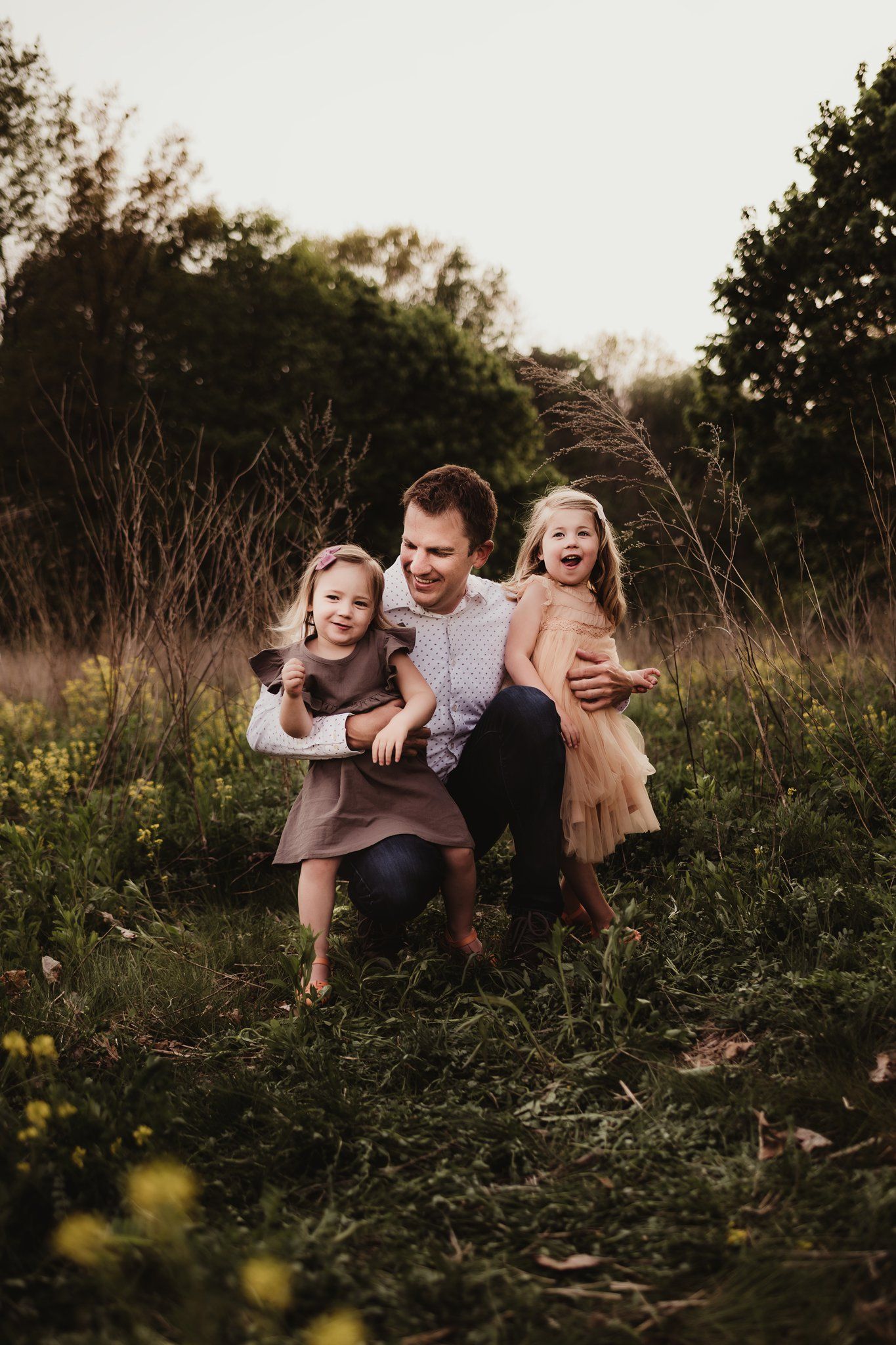 Joyful family portrait in a rustic field with coordinated casual outfits.