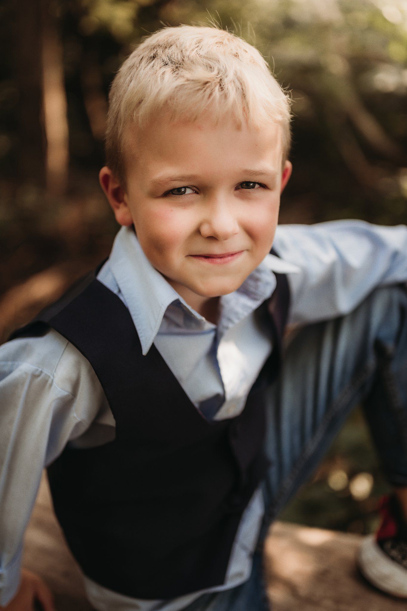 A portrait shows someone wearing a dress shirt and vest while smiling at the camera.