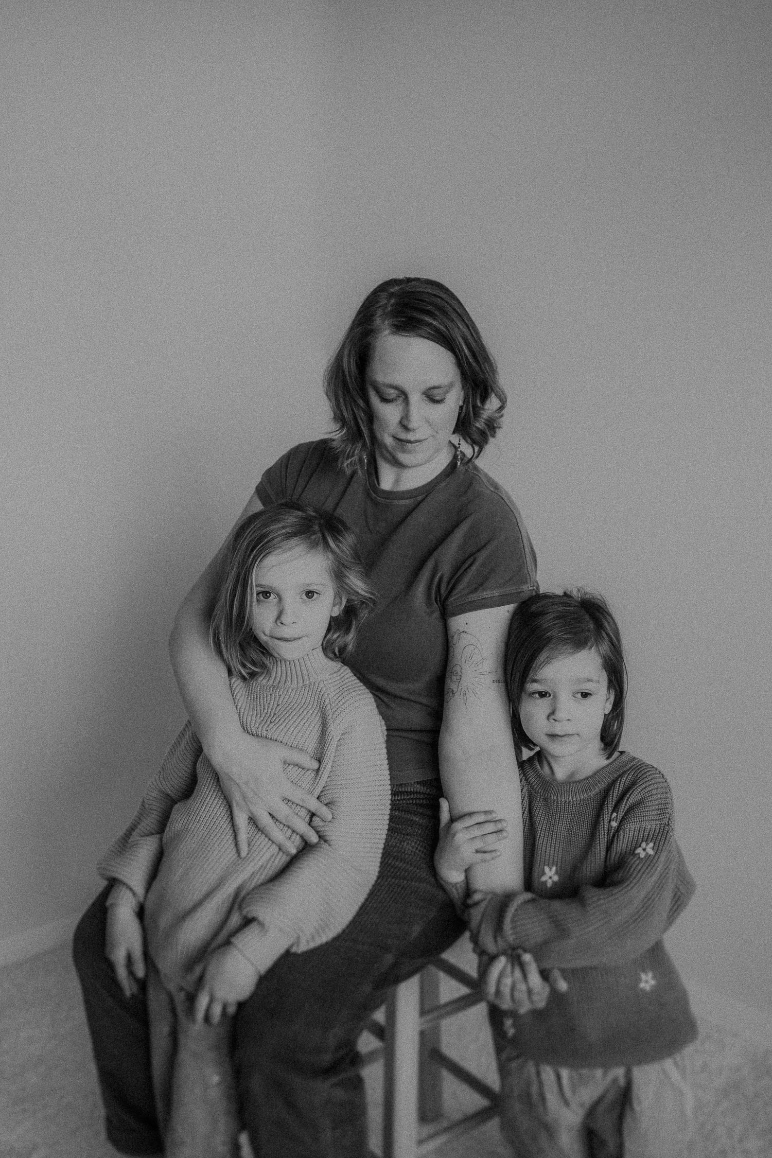 Black and white portrait of family members sitting together wearing sweaters against a plain background.