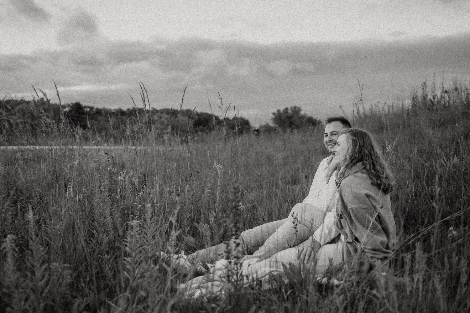Person dressed in white lounging in a peaceful meadow field in black and white.