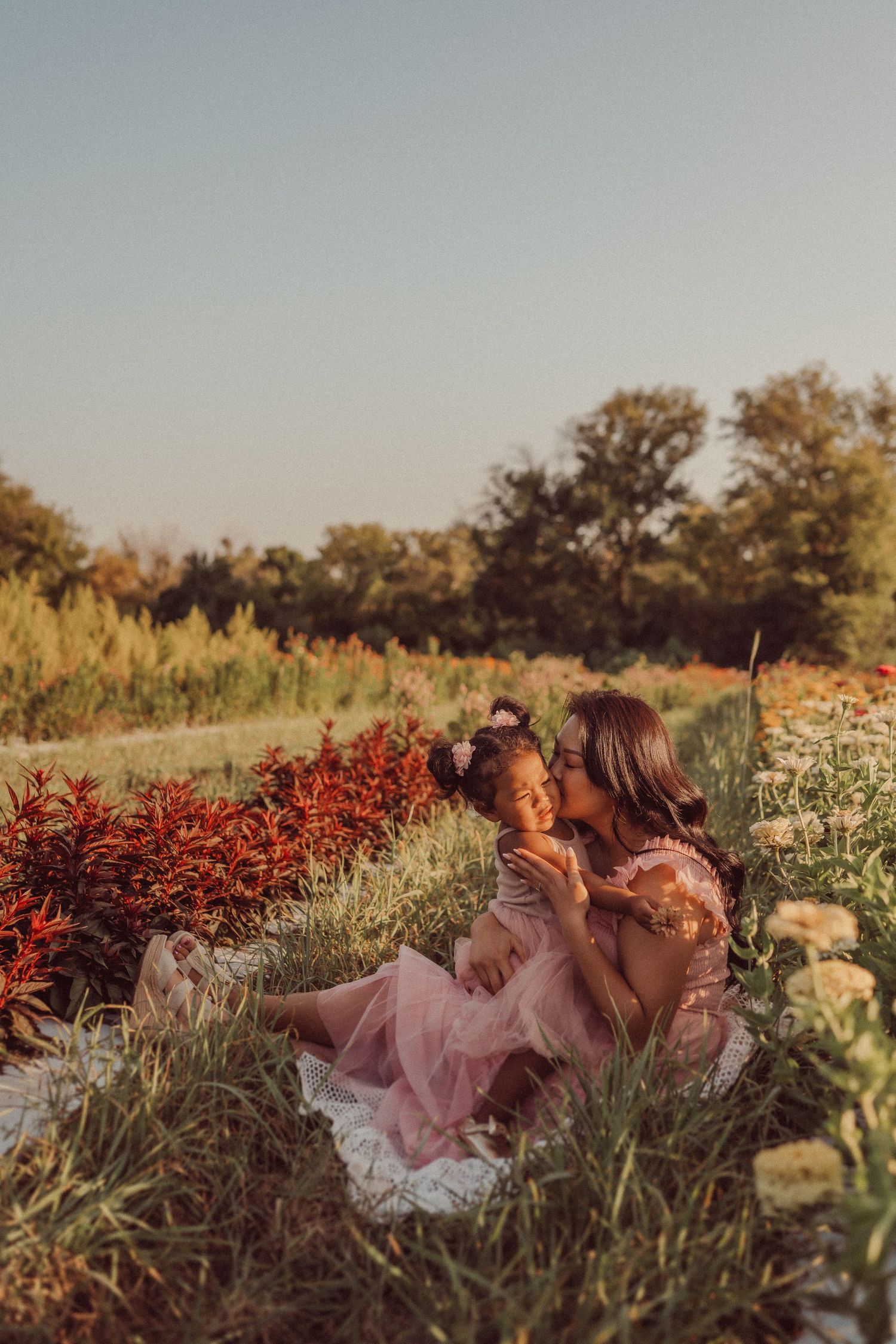 Intimate family moment captured in pink dress among autumn flowers.