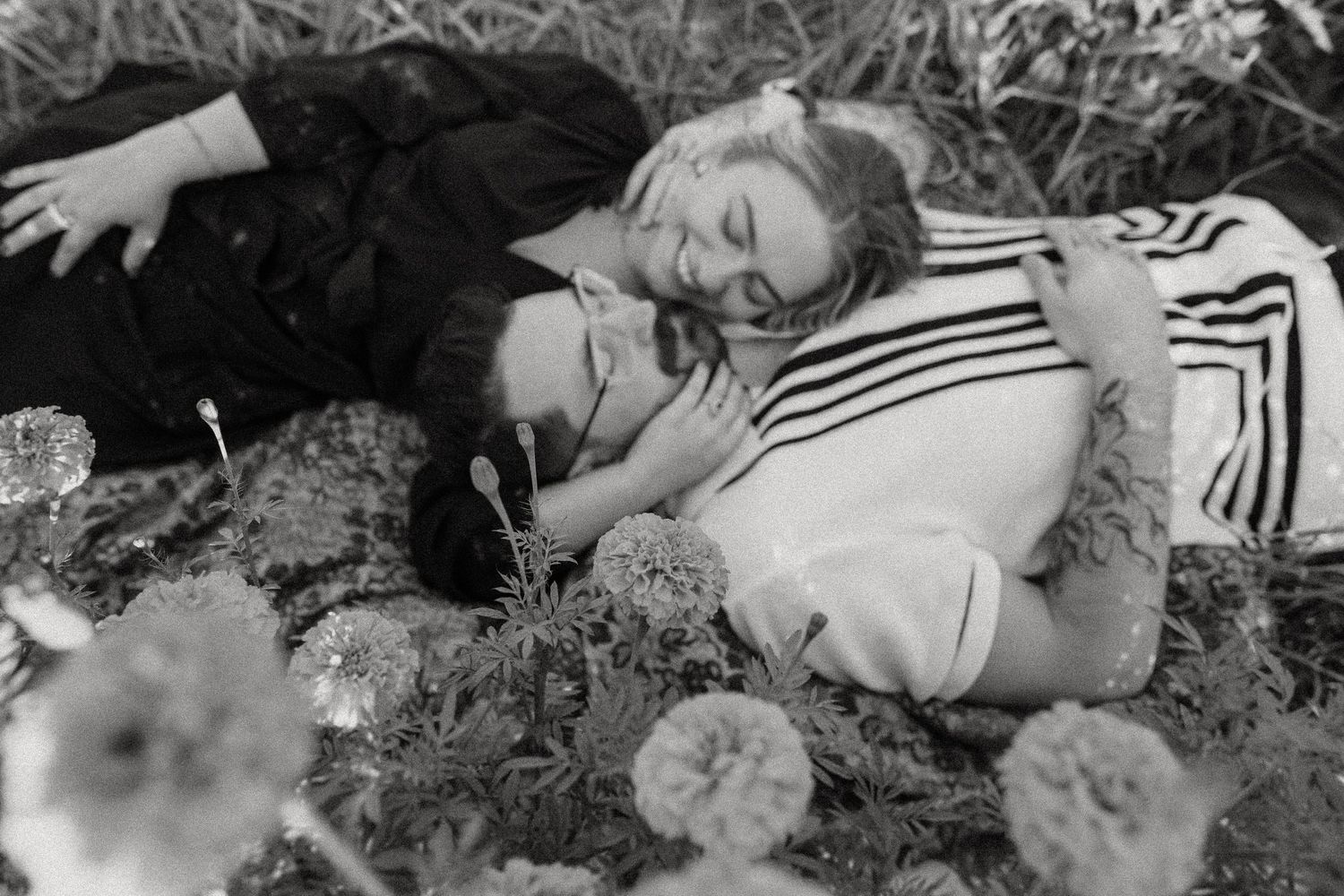 A black and white image of a couple resting in a flower field.