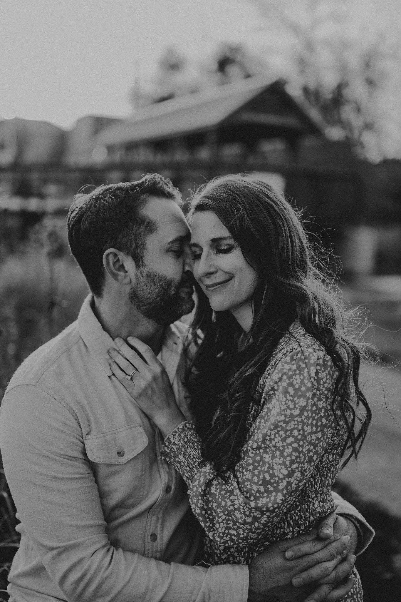 Black and white close-up portrait of a couple sharing an intimate moment outdoors.