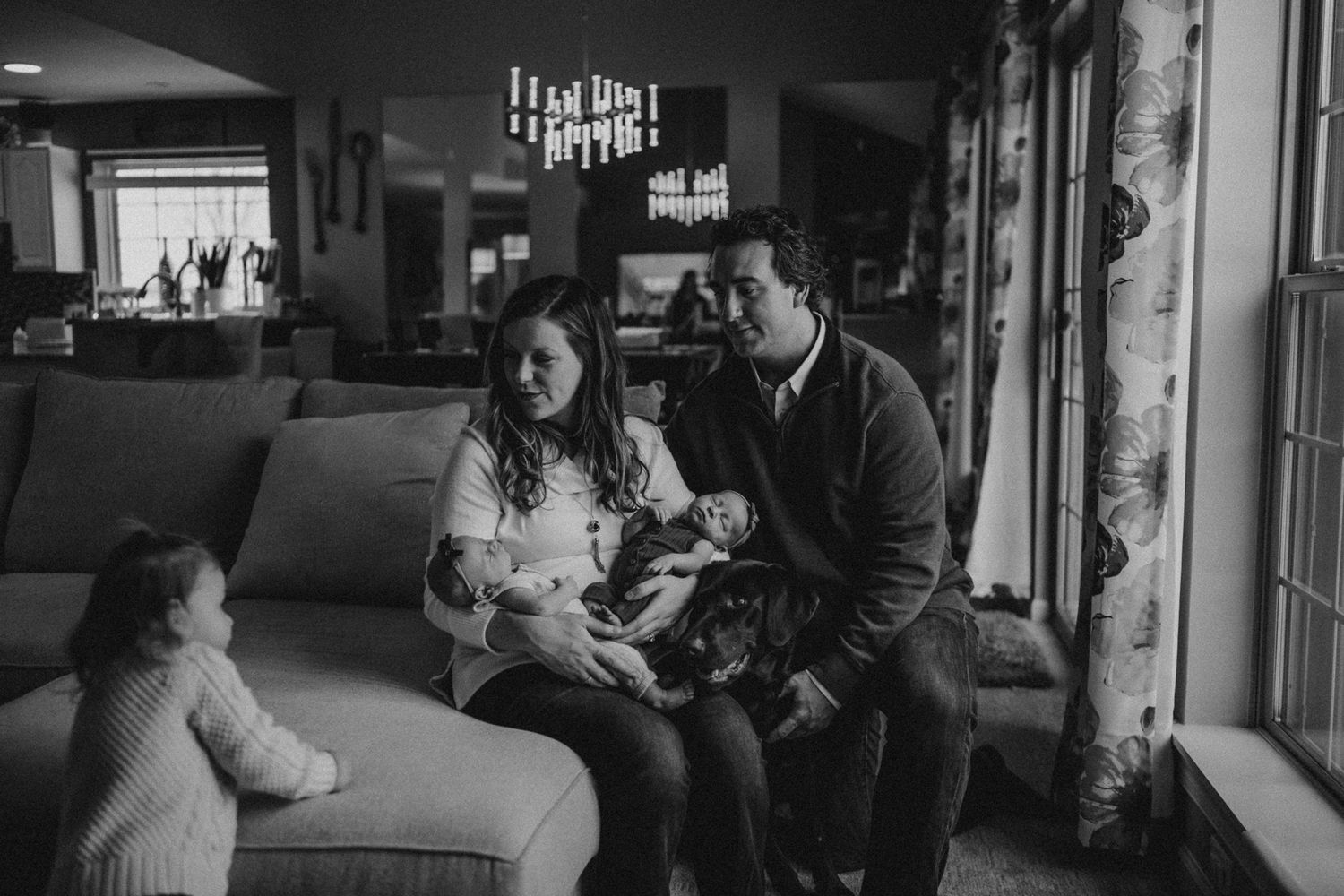 Black and white portrait of a family sharing an intimate moment on a comfortable couch.