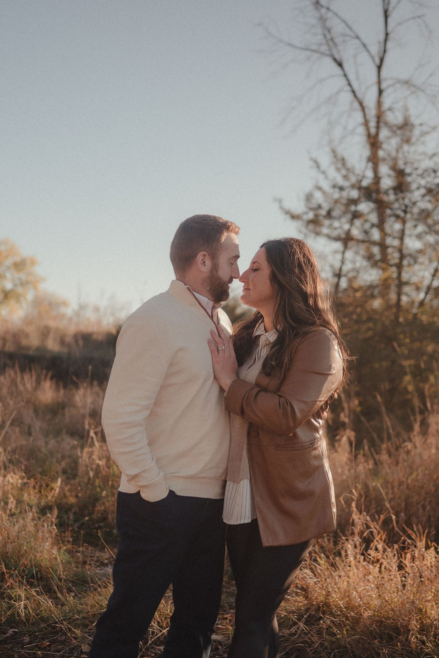 A couple shares an intimate moment together in a golden sunset field.