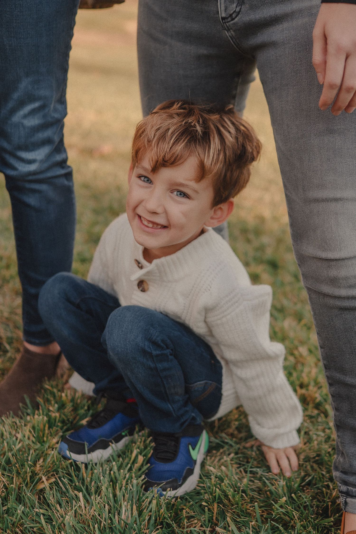 Close-up view of legs and feet on grass during an outdoor gathering.