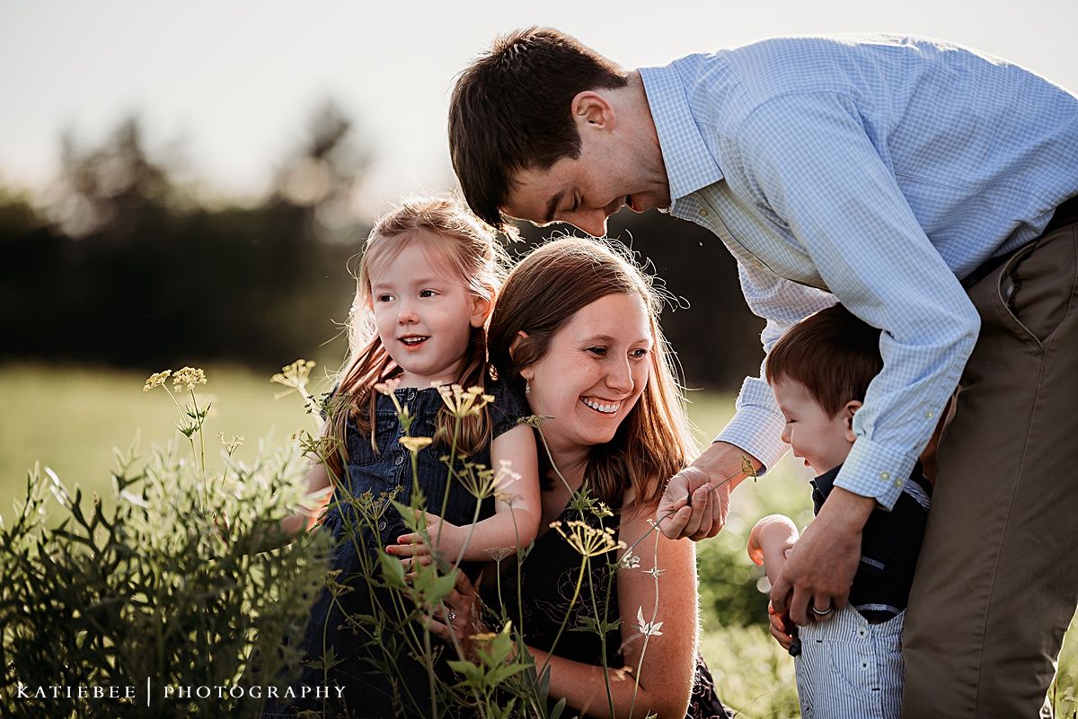 Family enjoying a candid moment together in a wildflower field at sunset.