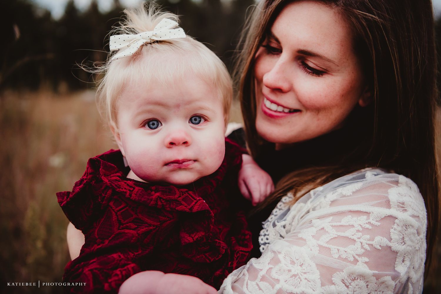 Tender moment between mother and child wearing matching lace and velvet outfits outdoors.
