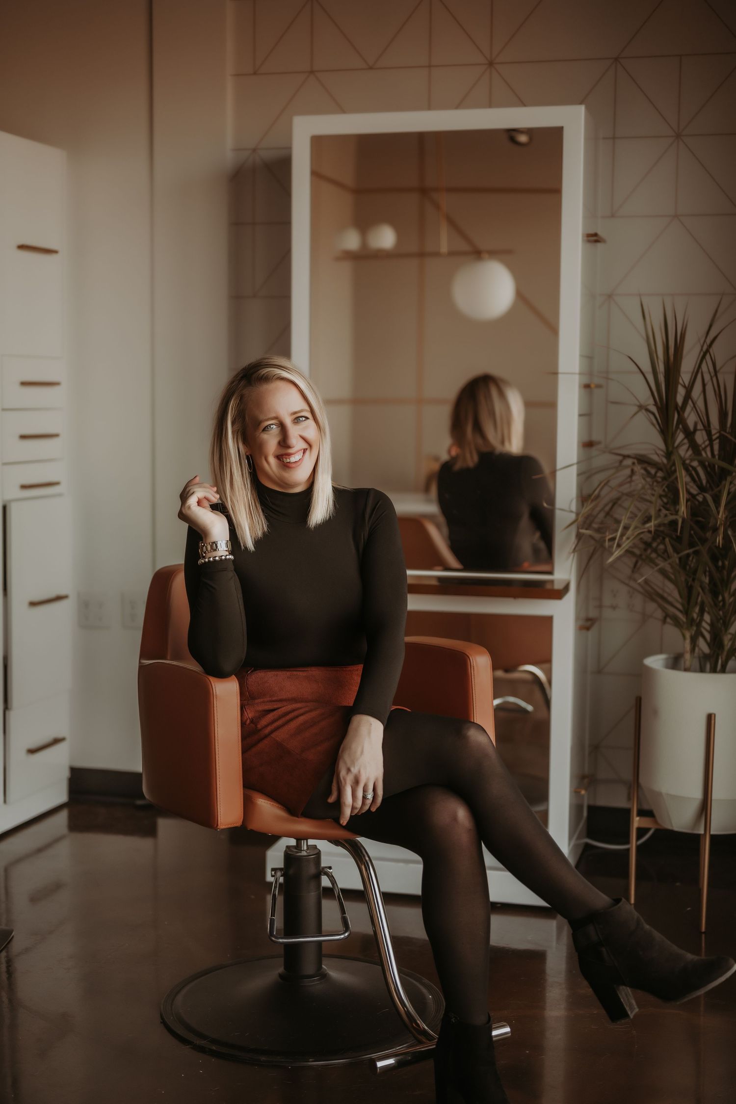 Stylish salon portrait featuring orange leather chair, mirror reflection, and modern interior design.