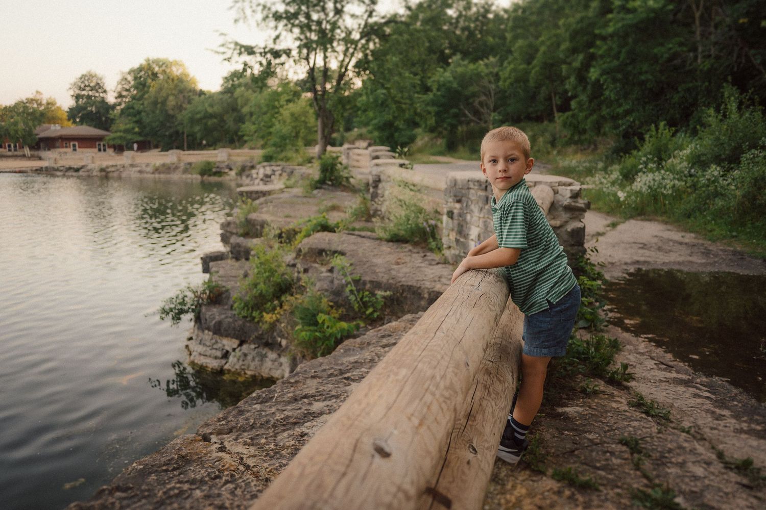 Family explores rocky shoreline near calm water during photo session.