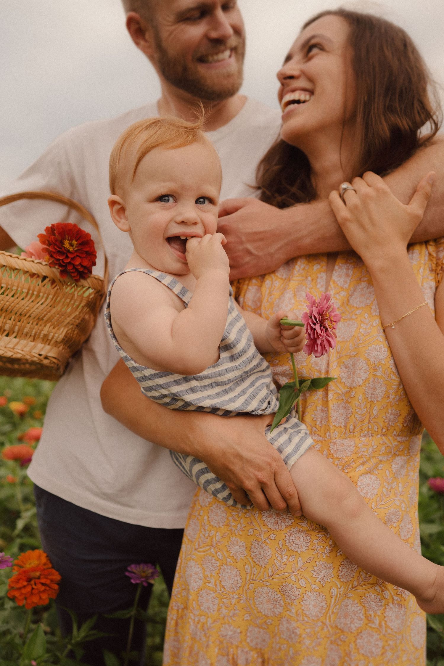 A family shares joyful moments together in a garden with blooming orange and pink flowers during golden hour lighting.