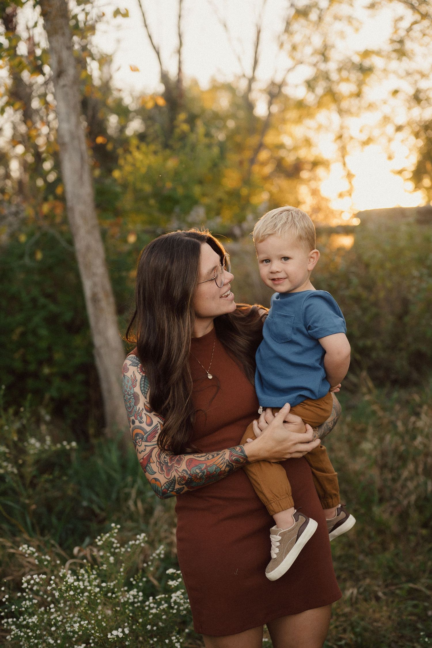 Mother and child share playful moments in an outdoor autumn setting.