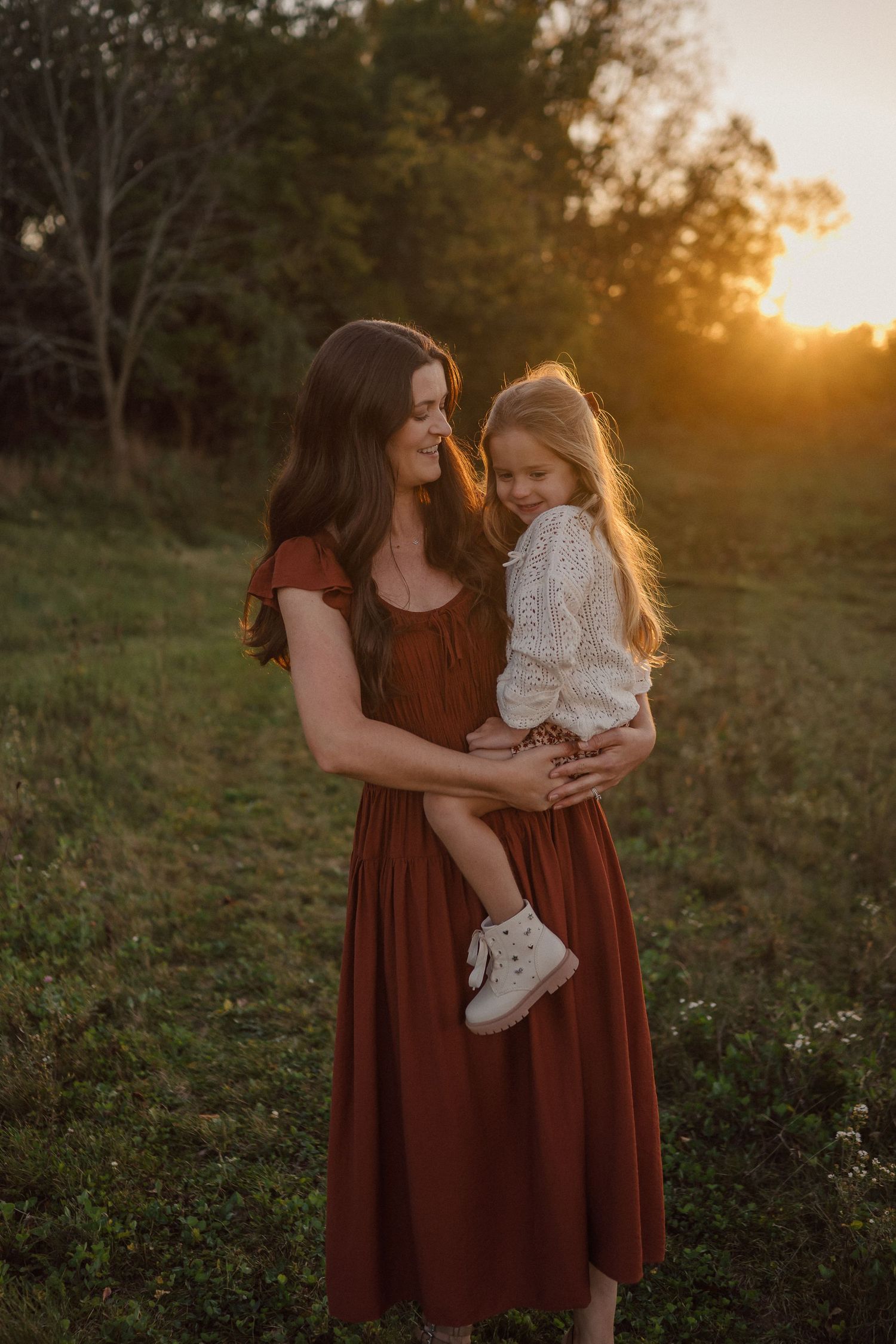 A loving family embraces in a sun-drenched field during golden hour, creating intimate outdoor portraits.