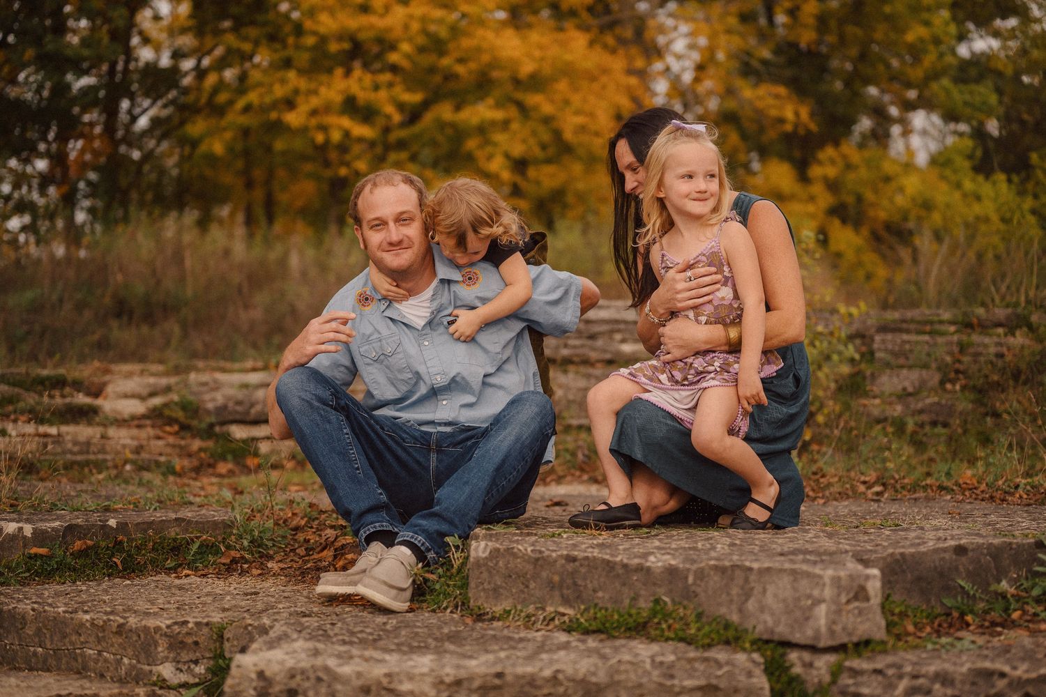 Family relaxing together on rocks during a warm autumn afternoon outdoors.