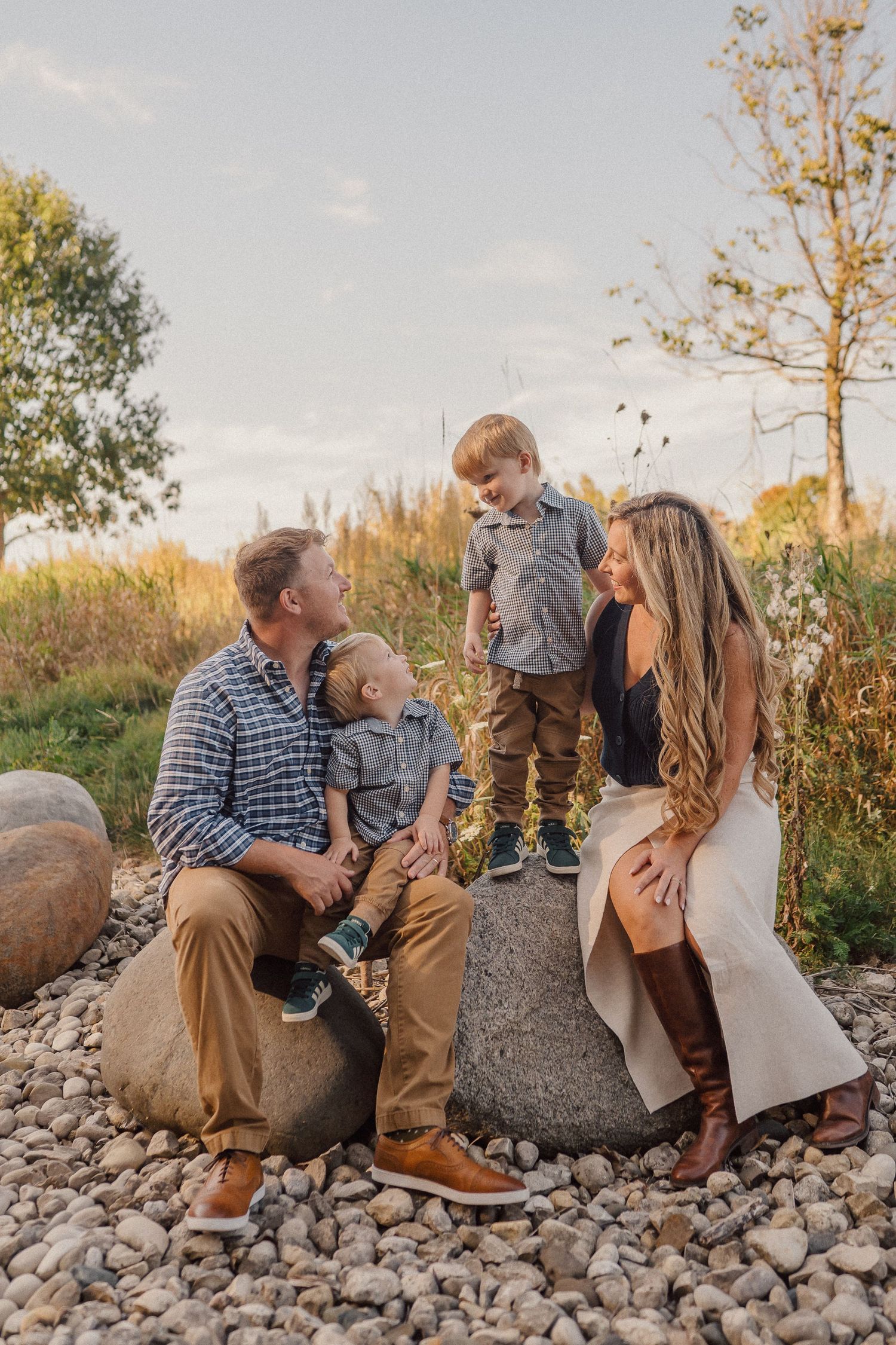 Family enjoying a tender moment together while sitting on rocky terrain during golden hour sunset.