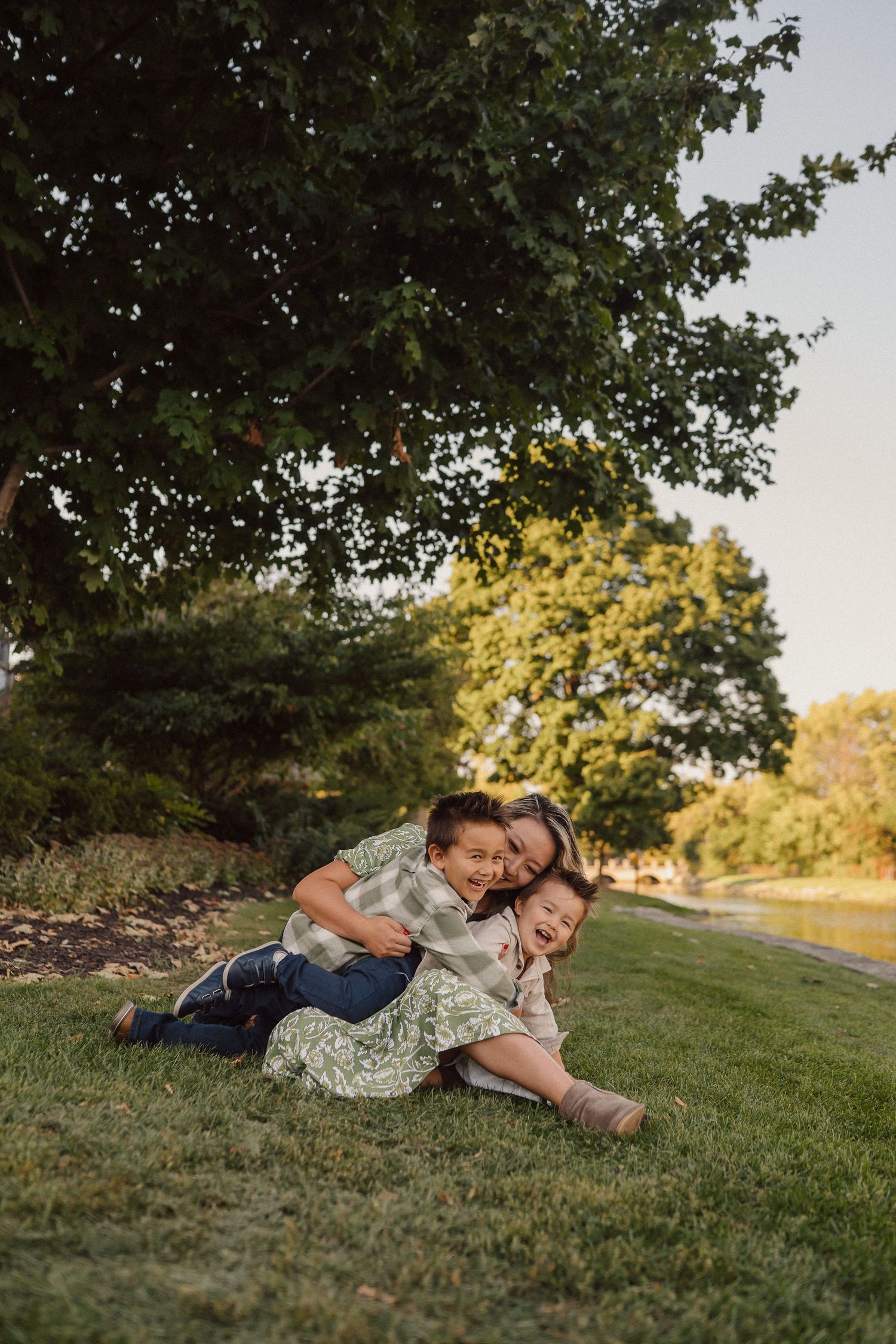 Two people lying together on a grassy hill during golden hour in a tender moment.