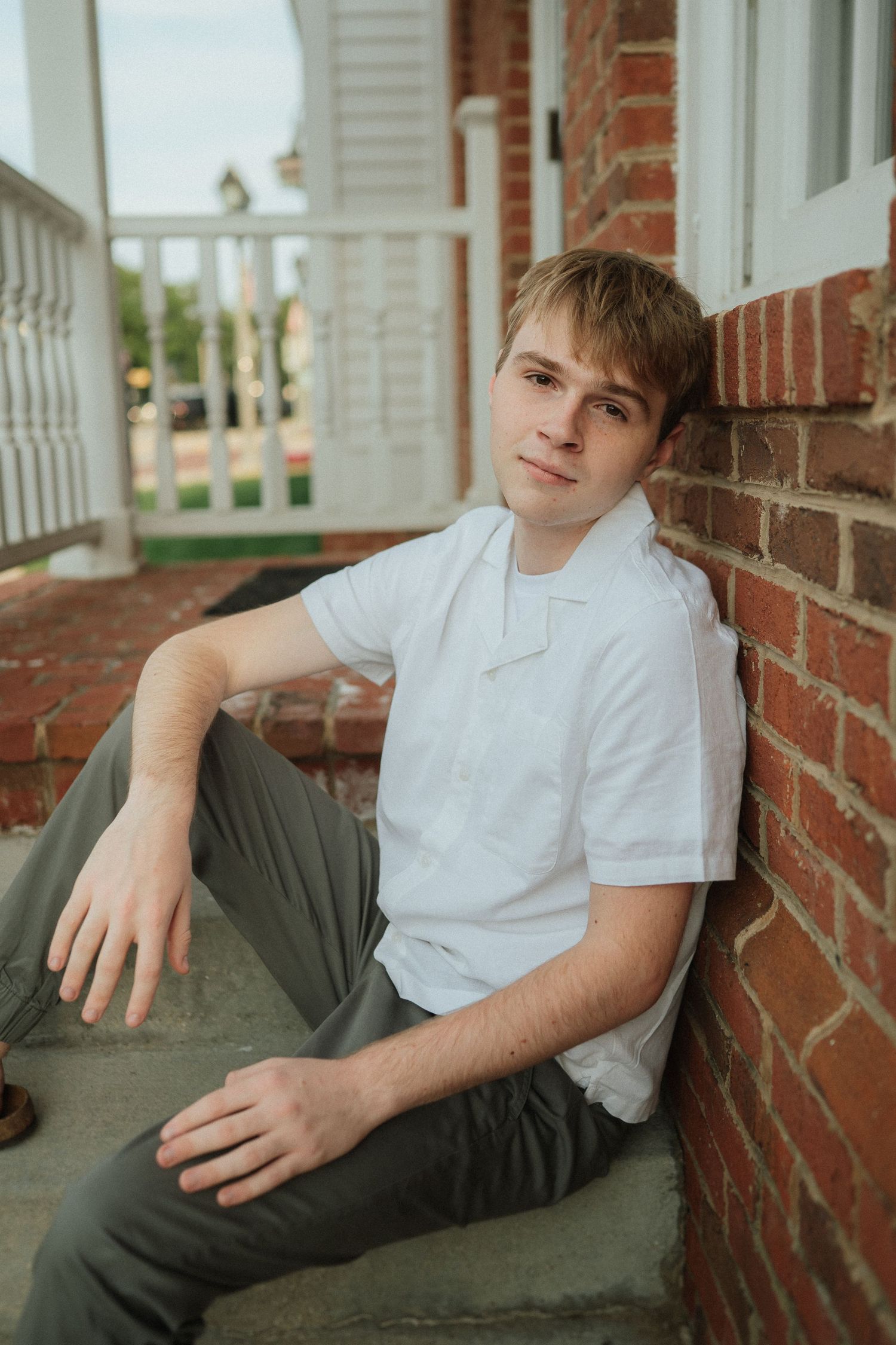A series of casual portraits showing someone relaxing on brick front porch steps in a white shirt and olive pants.