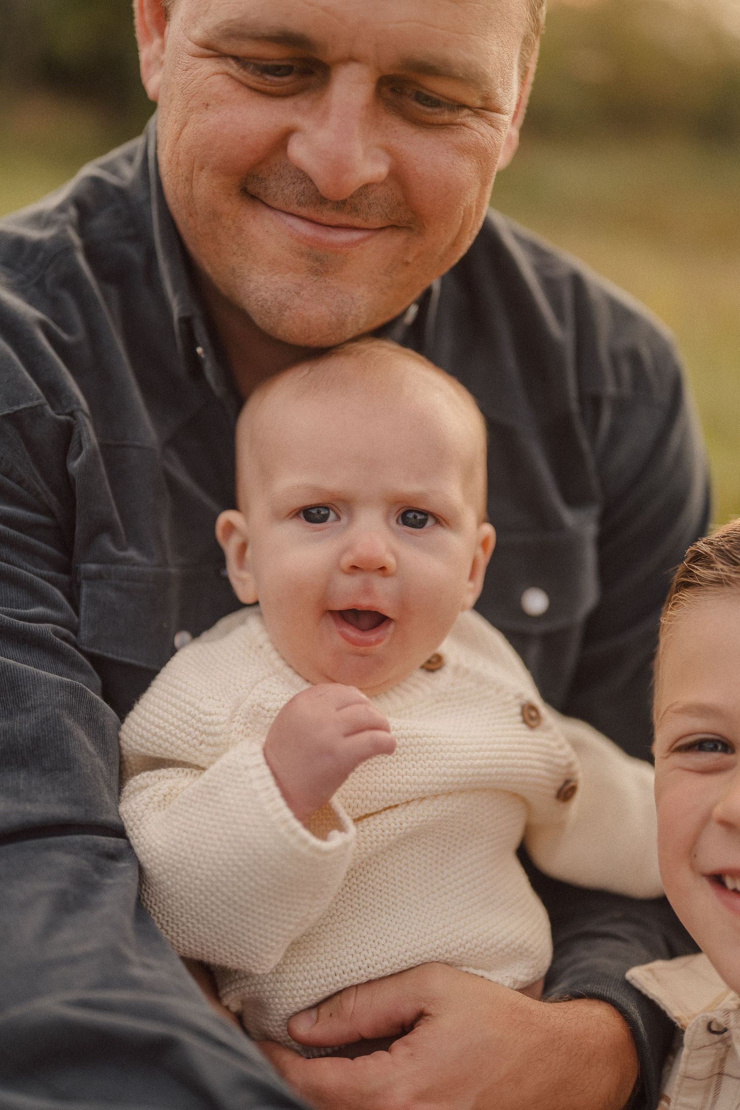 A series of candid moments showing a person in dark clothing holding and interacting with a baby in a cream sweater.