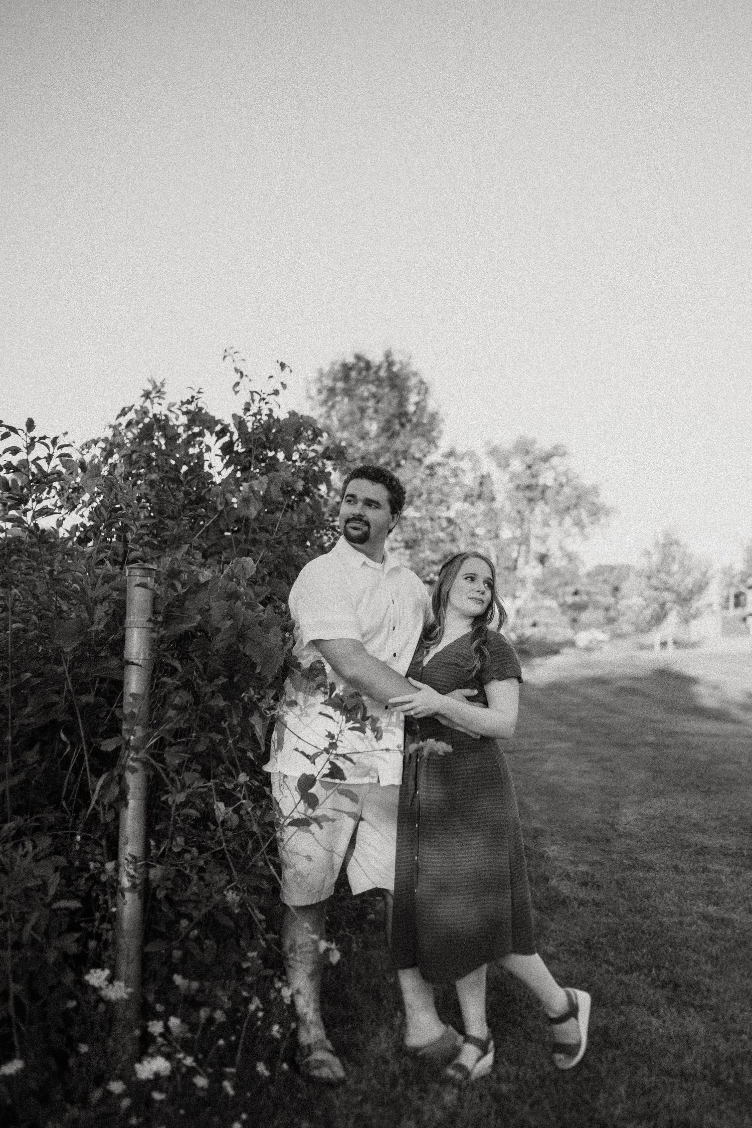 A romantic black and white portrait of a couple posing together in a garden setting.