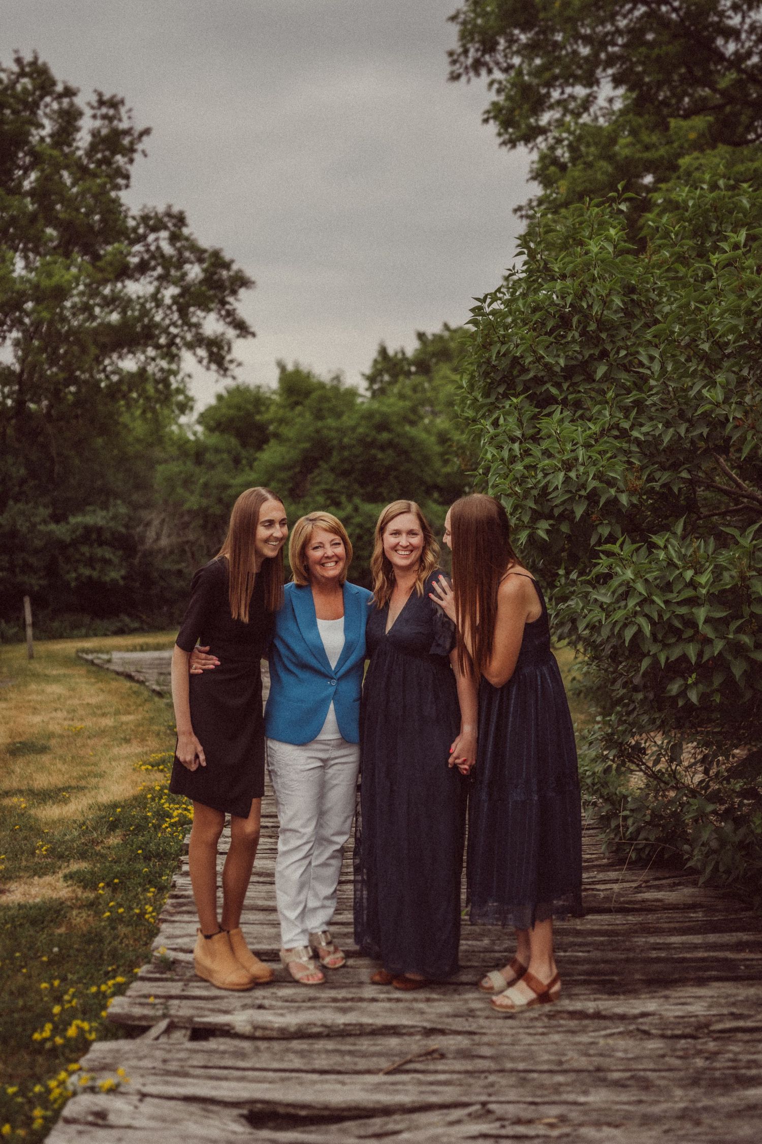 Group laughing together while standing on rustic wooden walkway surrounded by trees.