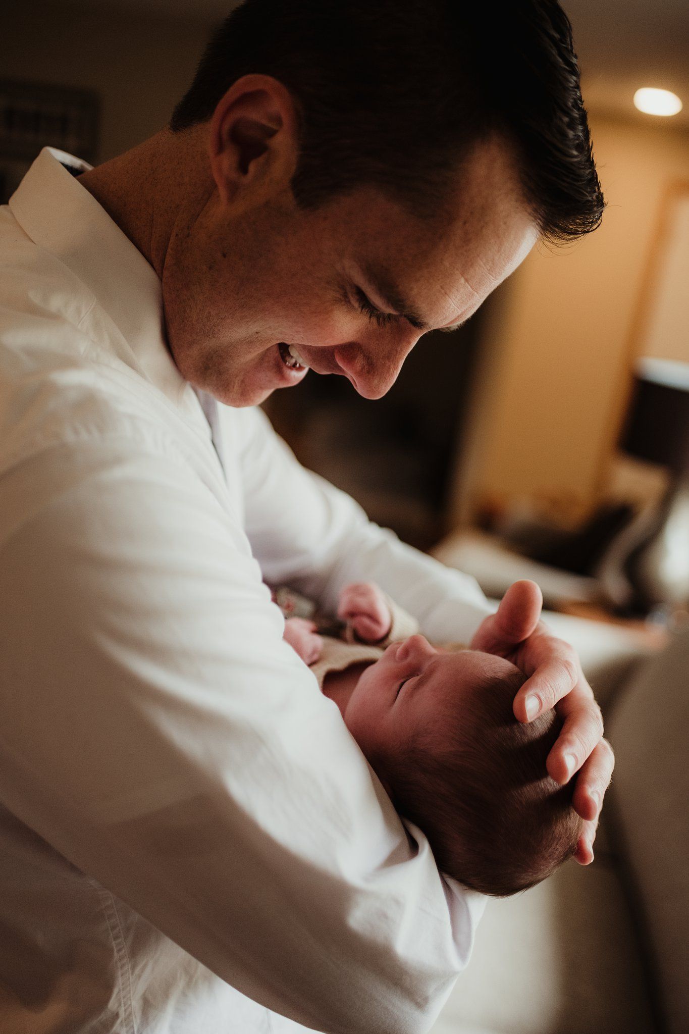 Intimate close-up moment between parent and newborn in warm lighting.