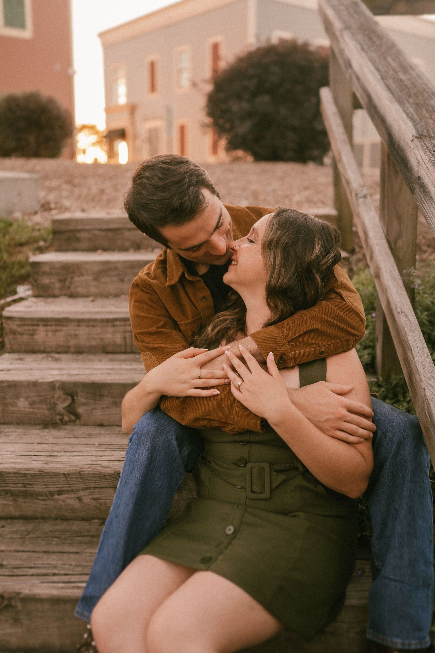 A tender moment between a couple on wooden stairs during sunset.