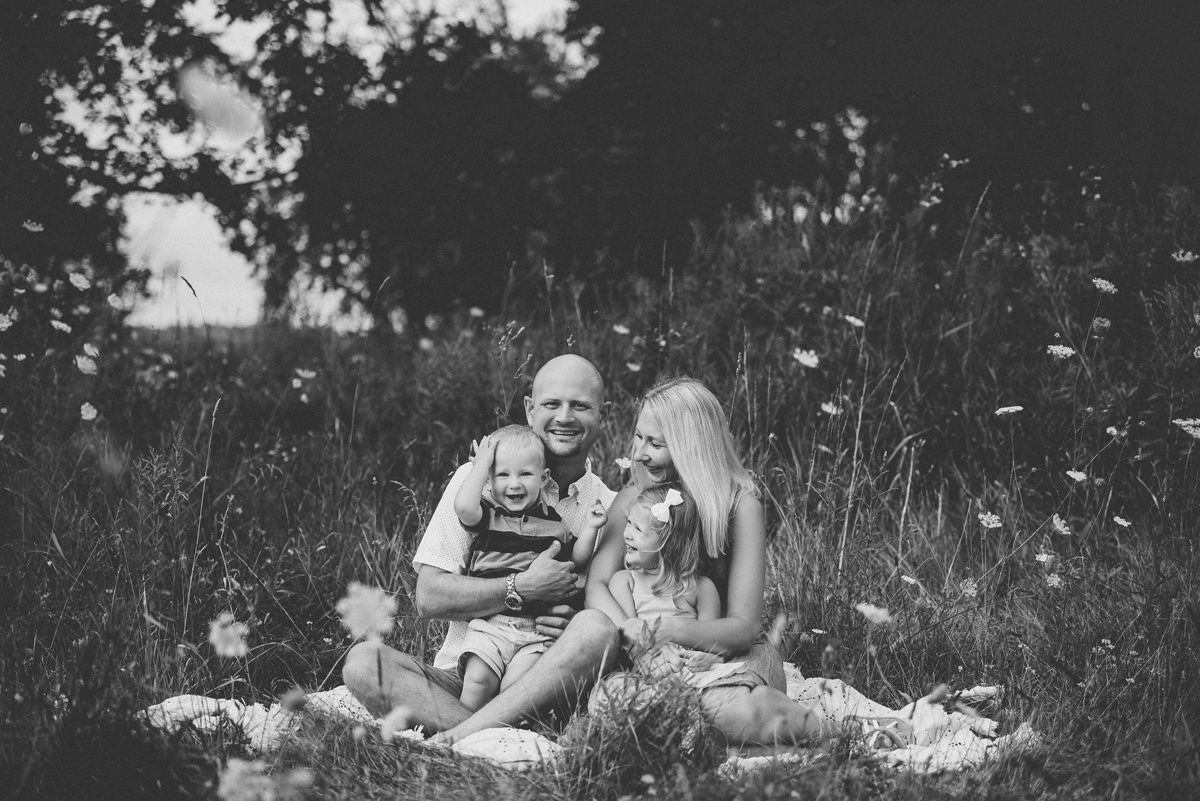 Black and white capture of a family sharing a loving moment in a meadow.