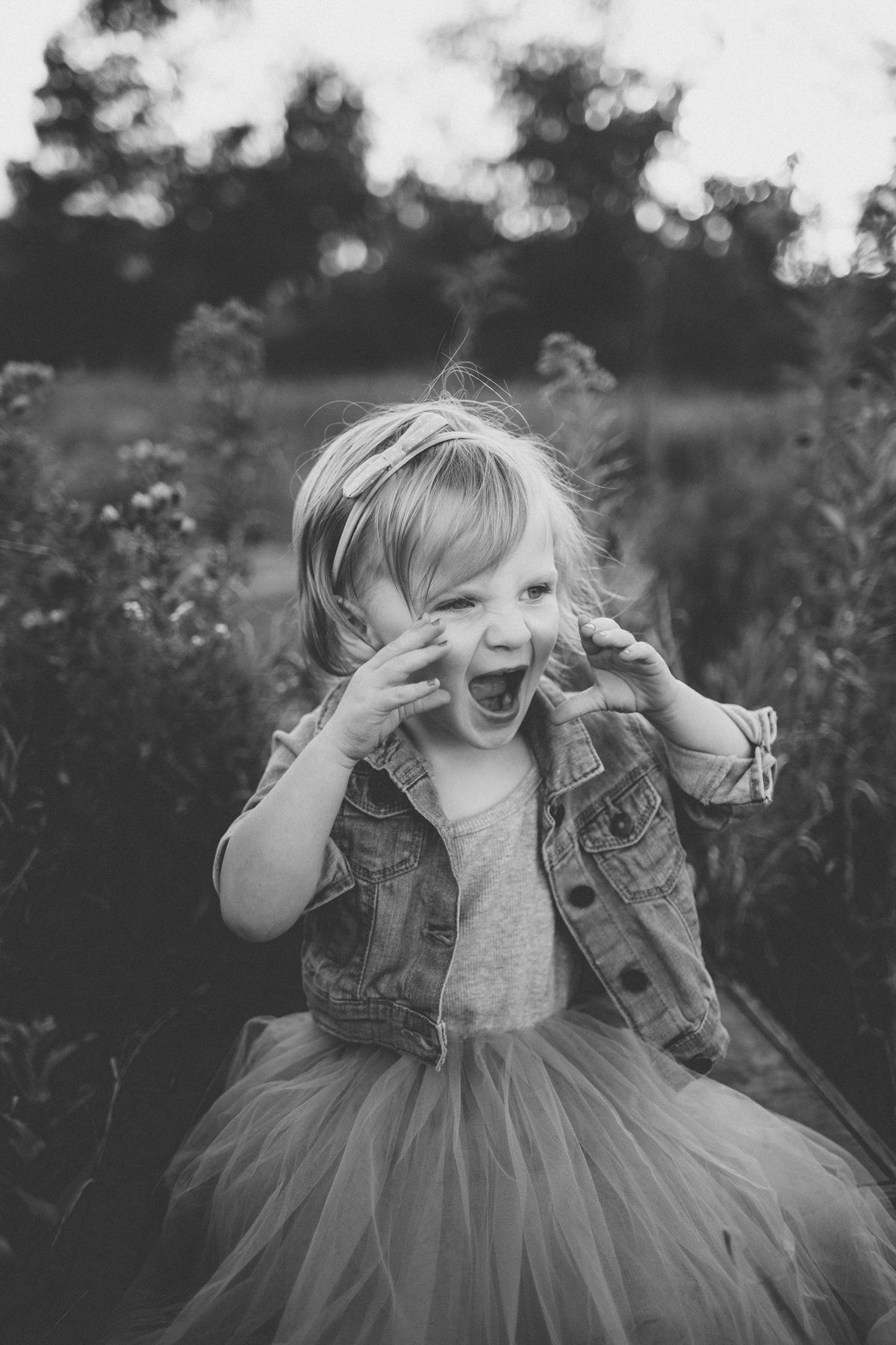Black and white portrait of pure joy and laughter while wearing a tulle skirt and denim jacket.