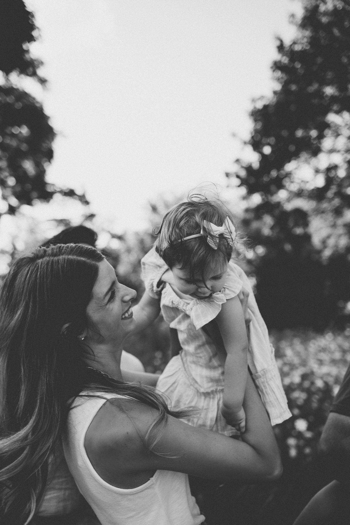 Black and white portrait of tender moment outdoors surrounded by trees.
