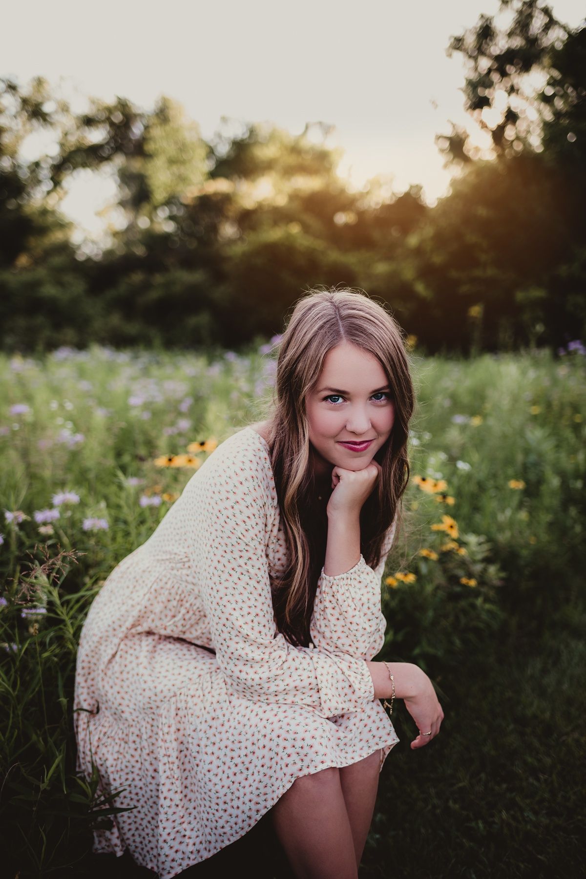 Sunset portrait in cream dress sitting among wildflowers in golden evening light.