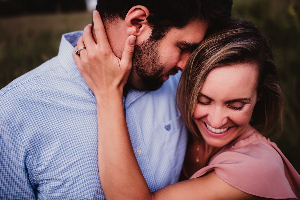 A couple laughing and embracing in close-up against a natural background.