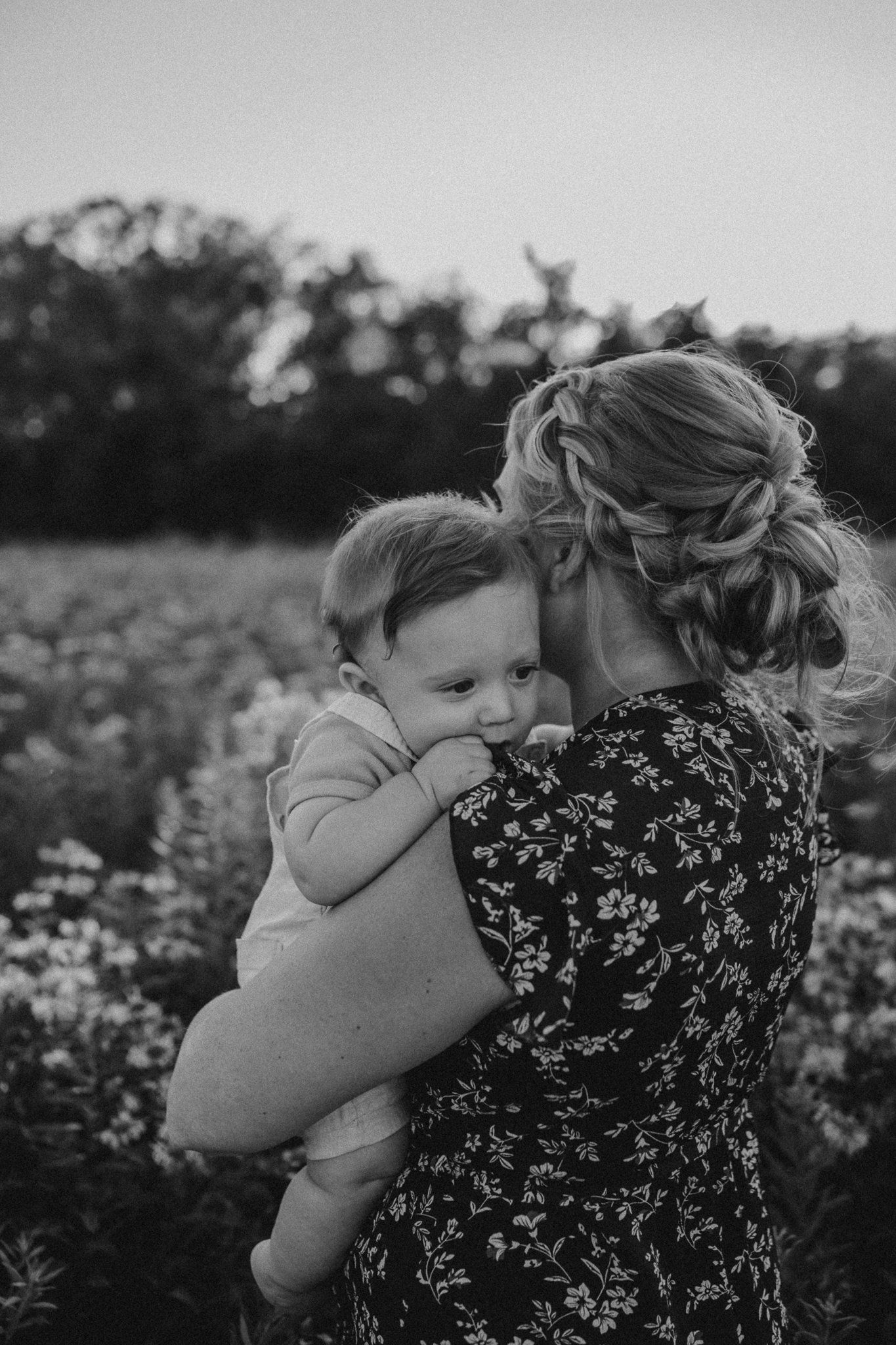 Black and white portrait capturing tender embrace in wildflower meadow.