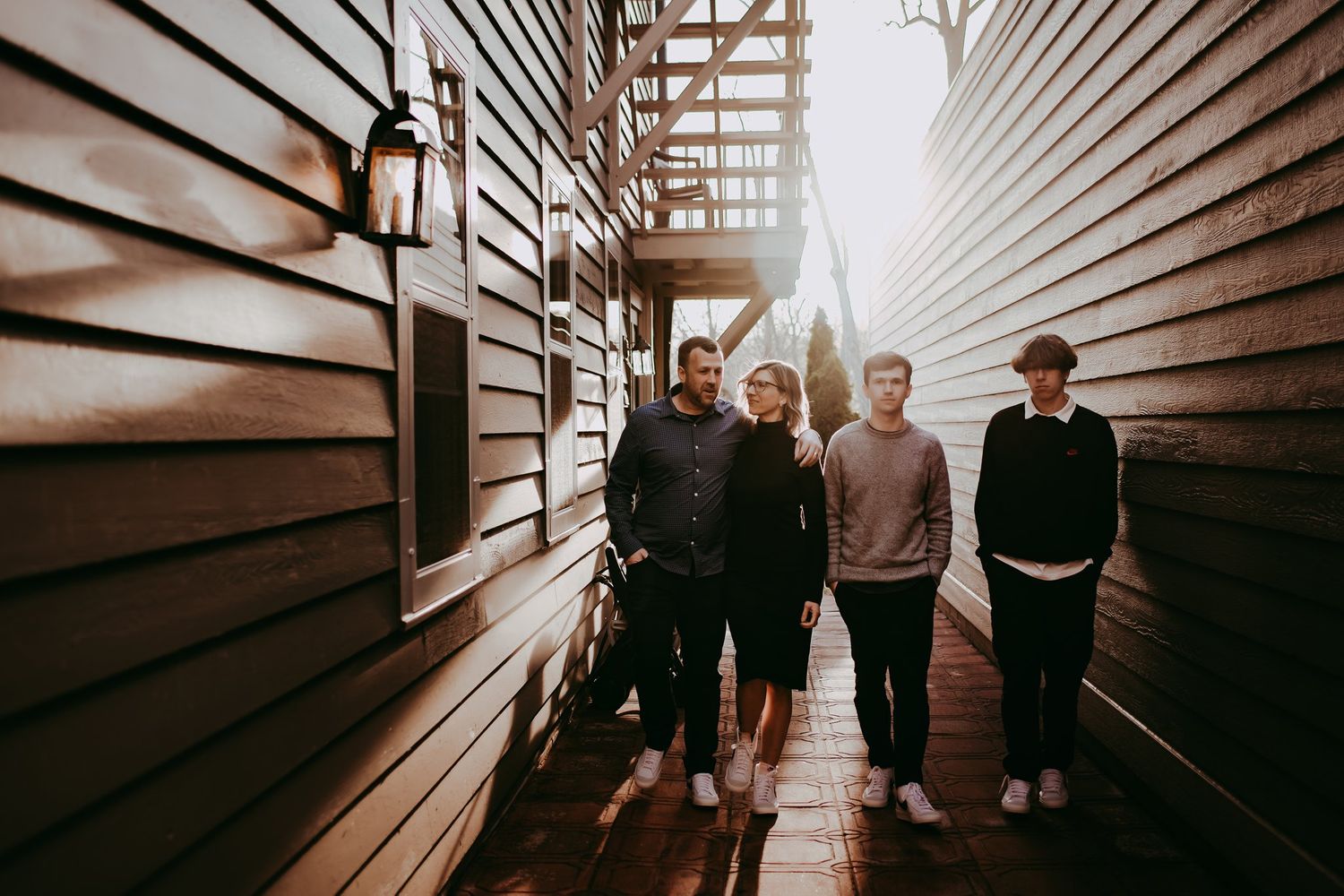 Group posing between wooden walls with fire escape visible above.