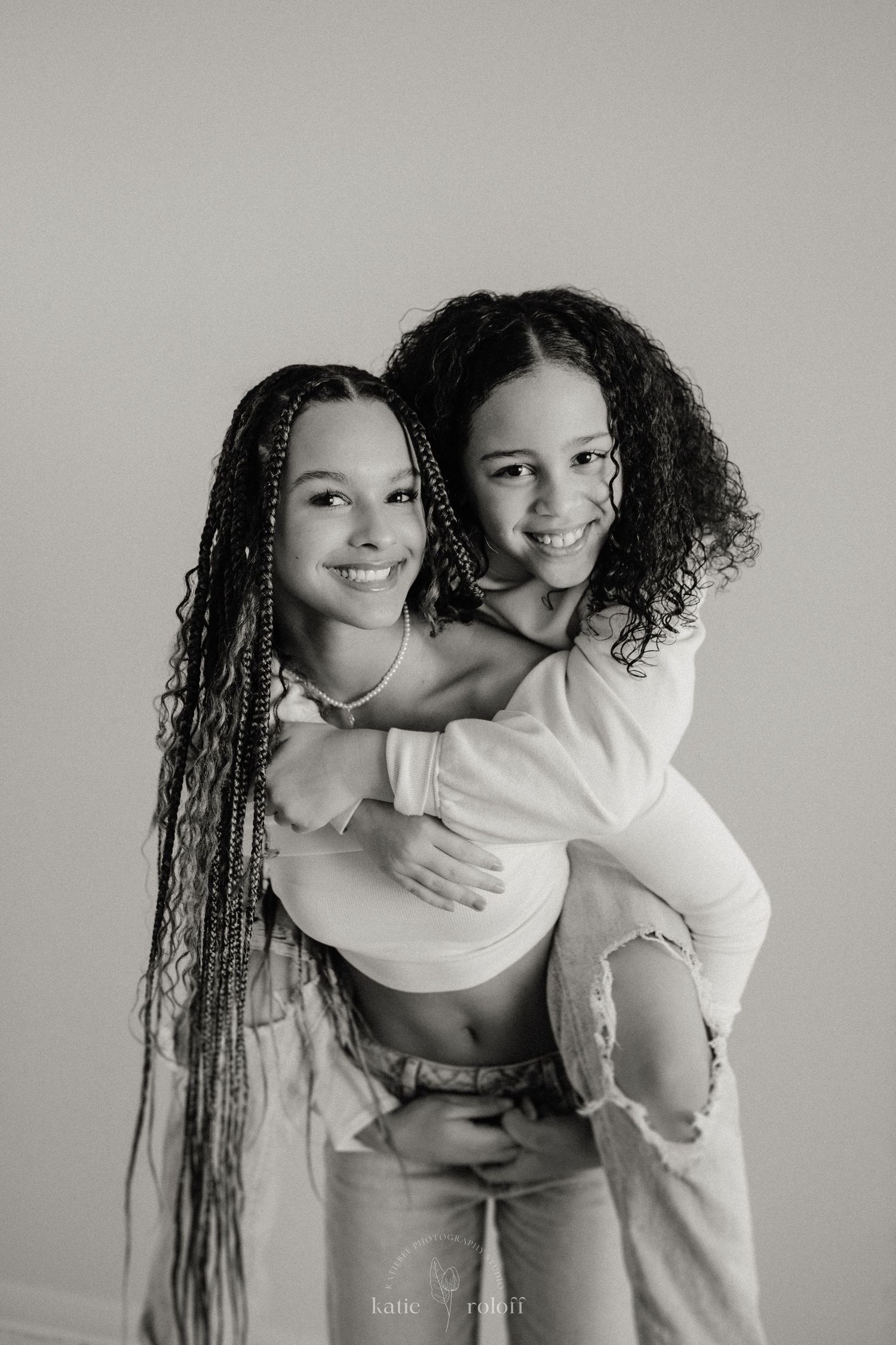 Black and white photo of two people embracing in a piggyback pose.