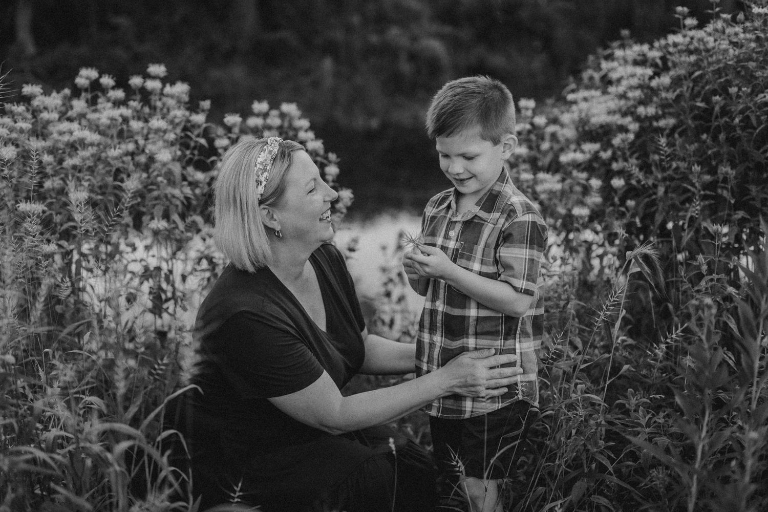 Candid black and white photo of joyful moment between parent and child in flower field.