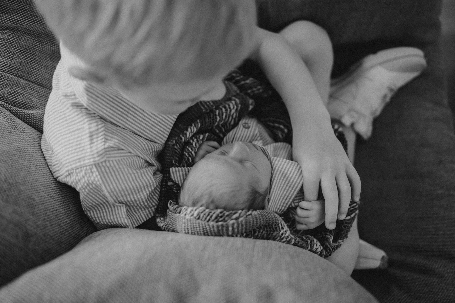 Black and white capture of siblings sharing a sweet moment on the couch.