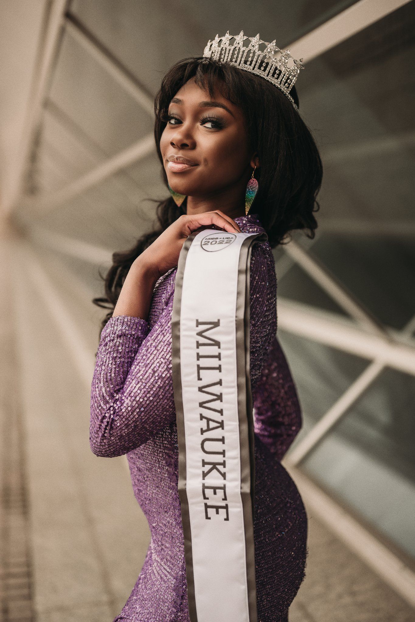 Close-up portrait of pageant winner in purple dress wearing crown and Milwaukee sash.