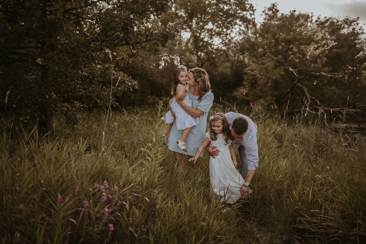 A family enjoys golden hour together in a grassy field during a lifestyle photoshoot.