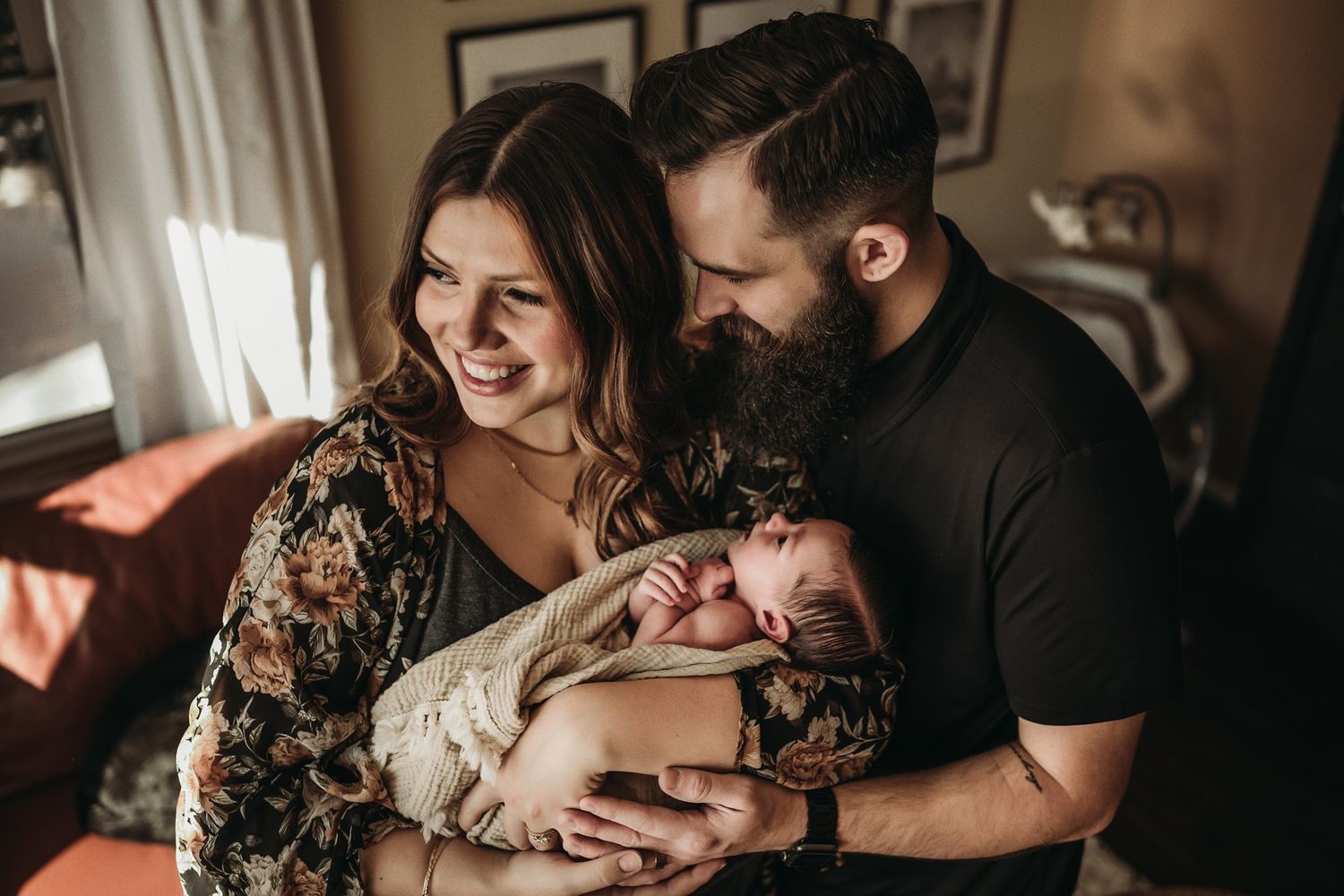 Warm lifestyle photo of new parents sharing intimate moment with baby at home.